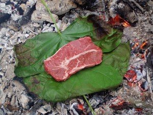 bushcraft equipment showing meat cooking on a leaf